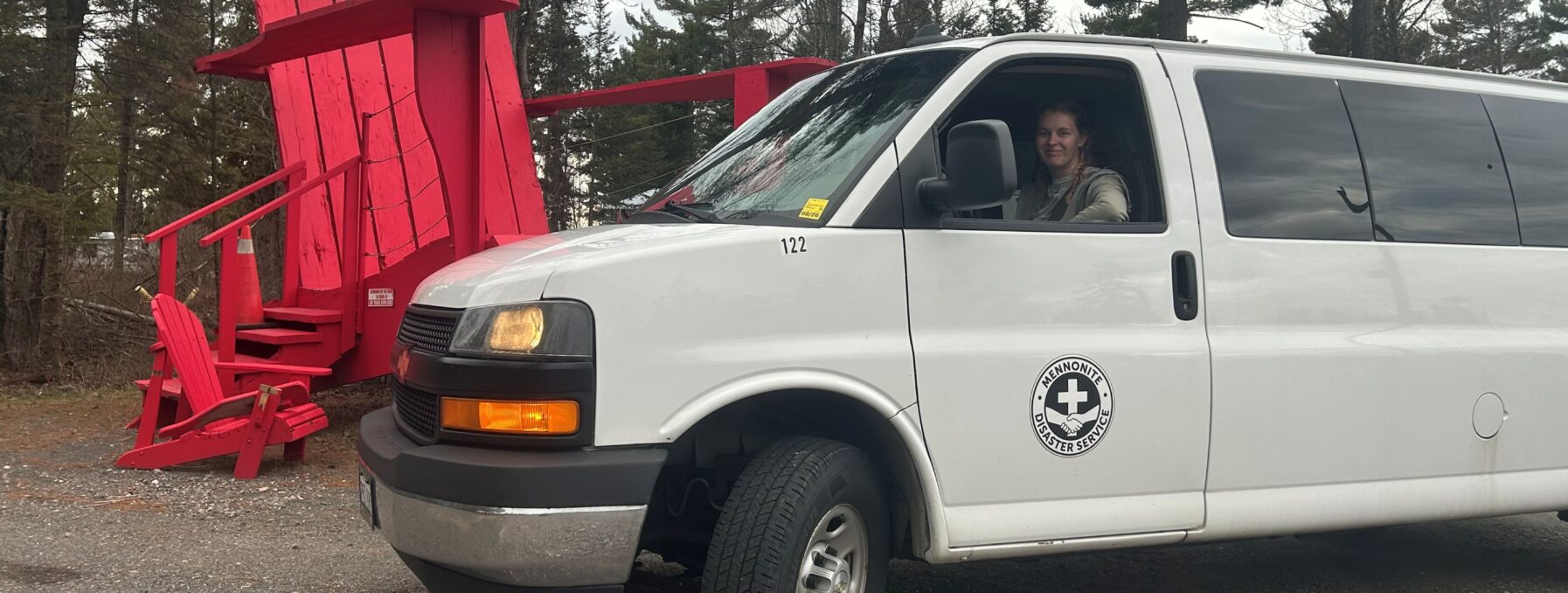 Van with driver in it beside iconic Canadian red cottae chair.