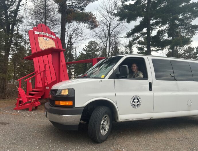 Van with driver in it beside iconic Canadian red cottae chair.