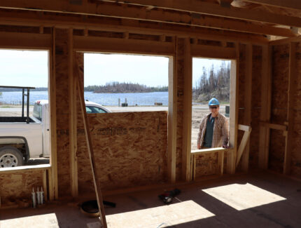 A volunteer looks through the window of a house in construction.